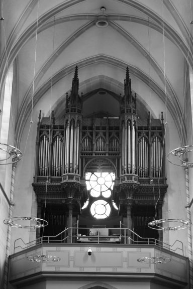 Details der Orgel in einer Kirche mit gotischem Design und einem großen rundem Fenster.