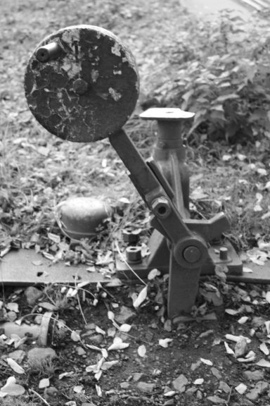 Alte Landmaschine mit einem runden Spiegel und rustikalem Metallrahmen auf dem Boden.